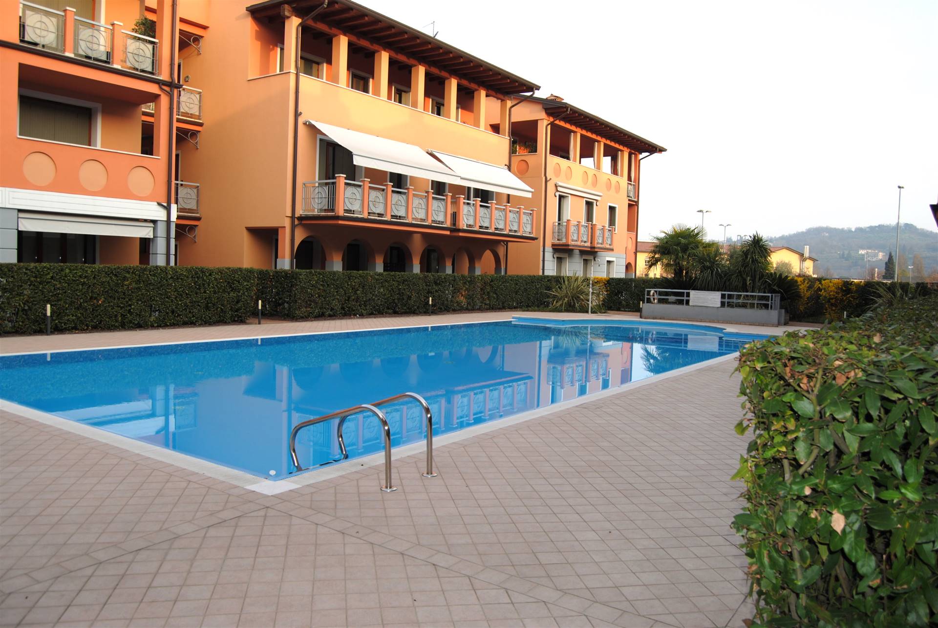 In zona centrale comoda al centro e al lago, in elegante complesso residenziale con piscina, vendiamo appartamento a piano terra composto da 